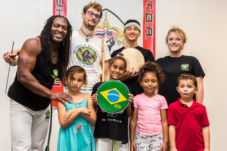 Battle Creek's Capoeira group holds the flag of Brazil, the country where the martial art they practice originated. Pictured back row from left, are Show Grande, Gameleira, Xavier, Angel, and front row from left, Gracie, Ava, Kari, and Jason. Photo by Susan Andress