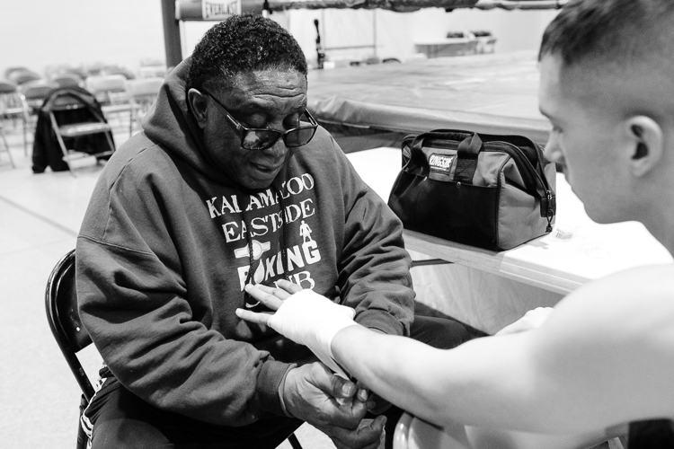 Coach Curtis Isaac tapes up a young boxer's hands before a match at the Eastside Boxing Show in February