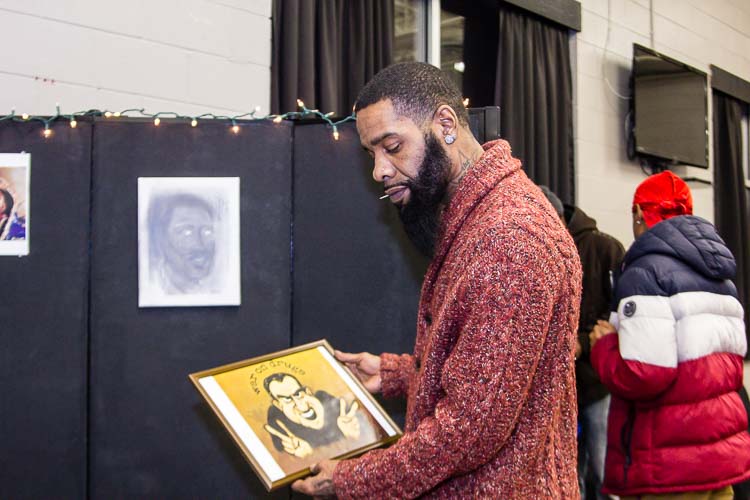 Ed Genesis, a featured artist for the Northside Art Hop, assembles his display of drawings.
