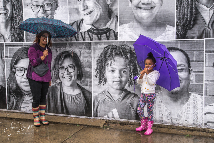 Colorful umbrellas proved a vibrant contrast to the black and white pictures of the streetside exhibit of neighbors' faces. Photo by Fran Dwight