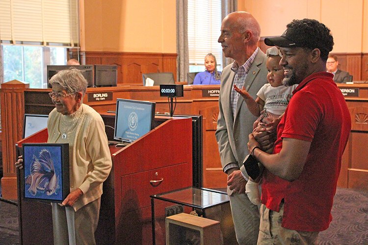 Tsugi Ogane holds a painting of a koi by Kalamazoo artist Gay Walker.given to her by the City of Kalamazoo. At center is Kalamazoo Mayor David Anderson and at right is former city commissioner Eric Cunningham who has visited Namuzu.
