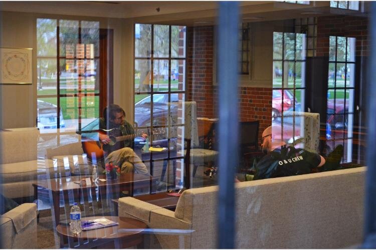 From the outside of the meeting room, the group strums their guitars as they wait for the start time.