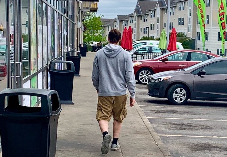 A man walks casually along a row of Campus Pointe Mall businesses on Monday, May 8, 2023. The are has been plagued in recent months with gun violence and weekend visitors who loiter in their cars.