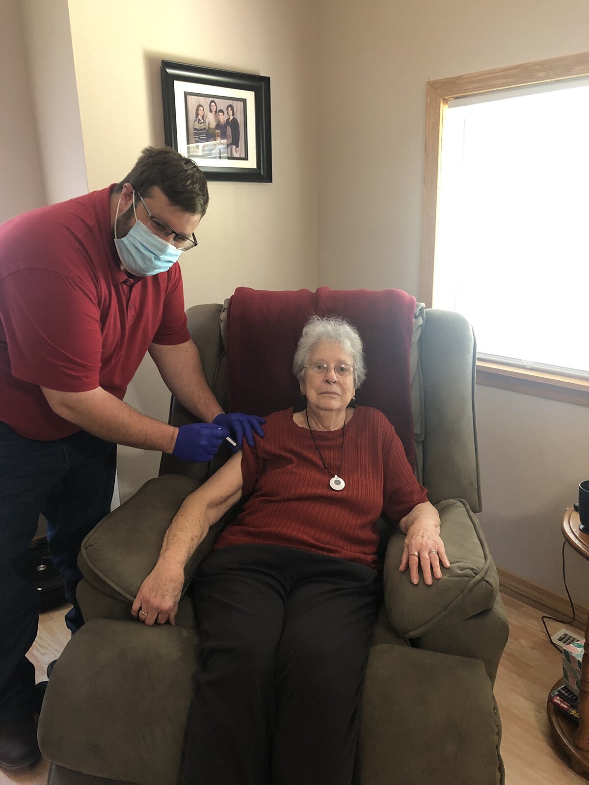 Nathaniel Bergman administers a COVID-19 vaccine to a homebound resident in her home.