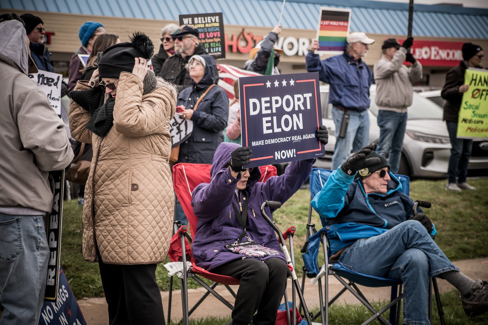 Kalamazoo residents Mary Lou Sedlock and Ron Zellers, seated, say they're anti-Trump, anti-Musk, and pro-democracy.