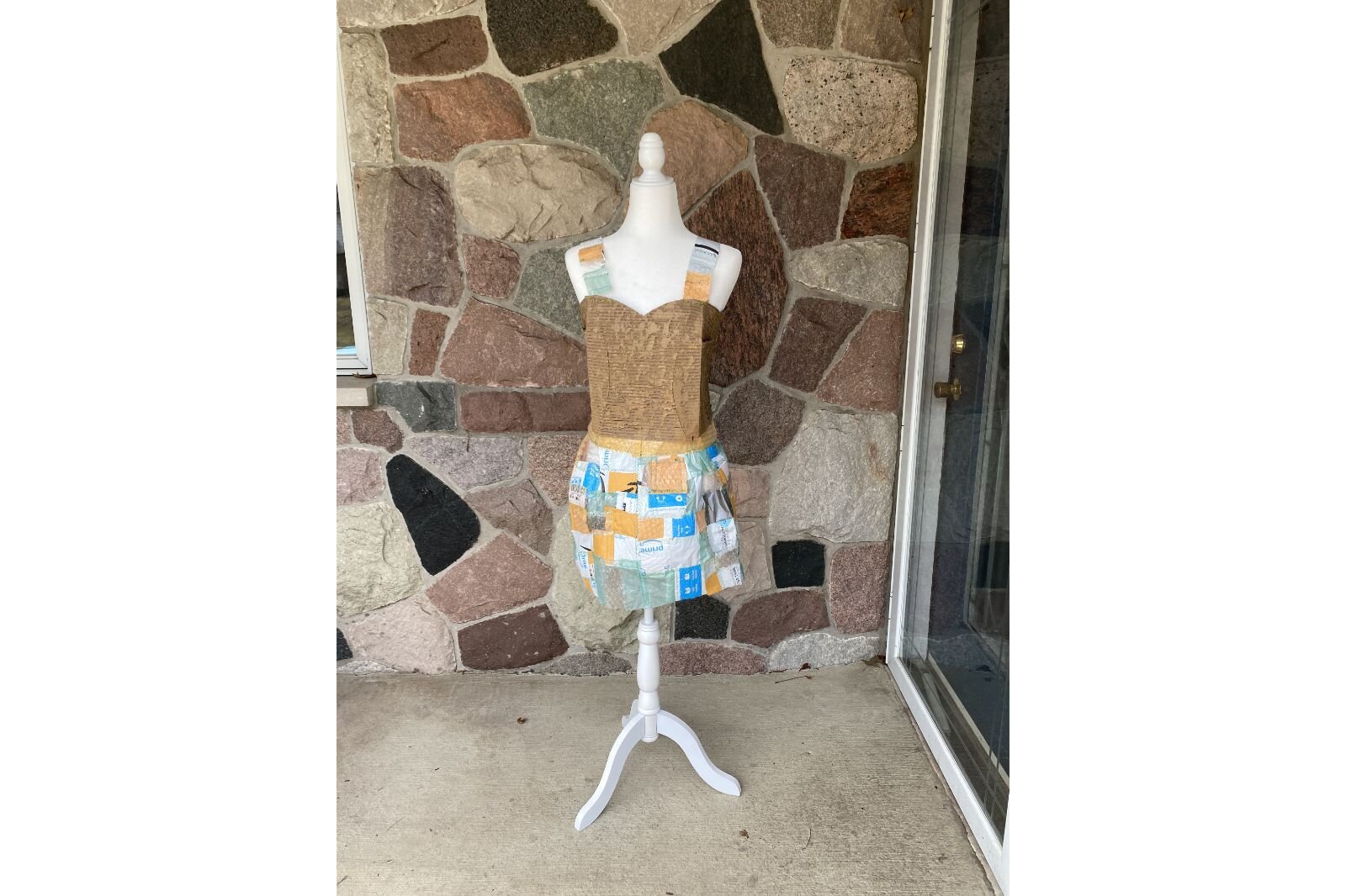 The finished “Plastic Patchwork Packing Dress” is appropriately showcased on a doorstep where a package might land.