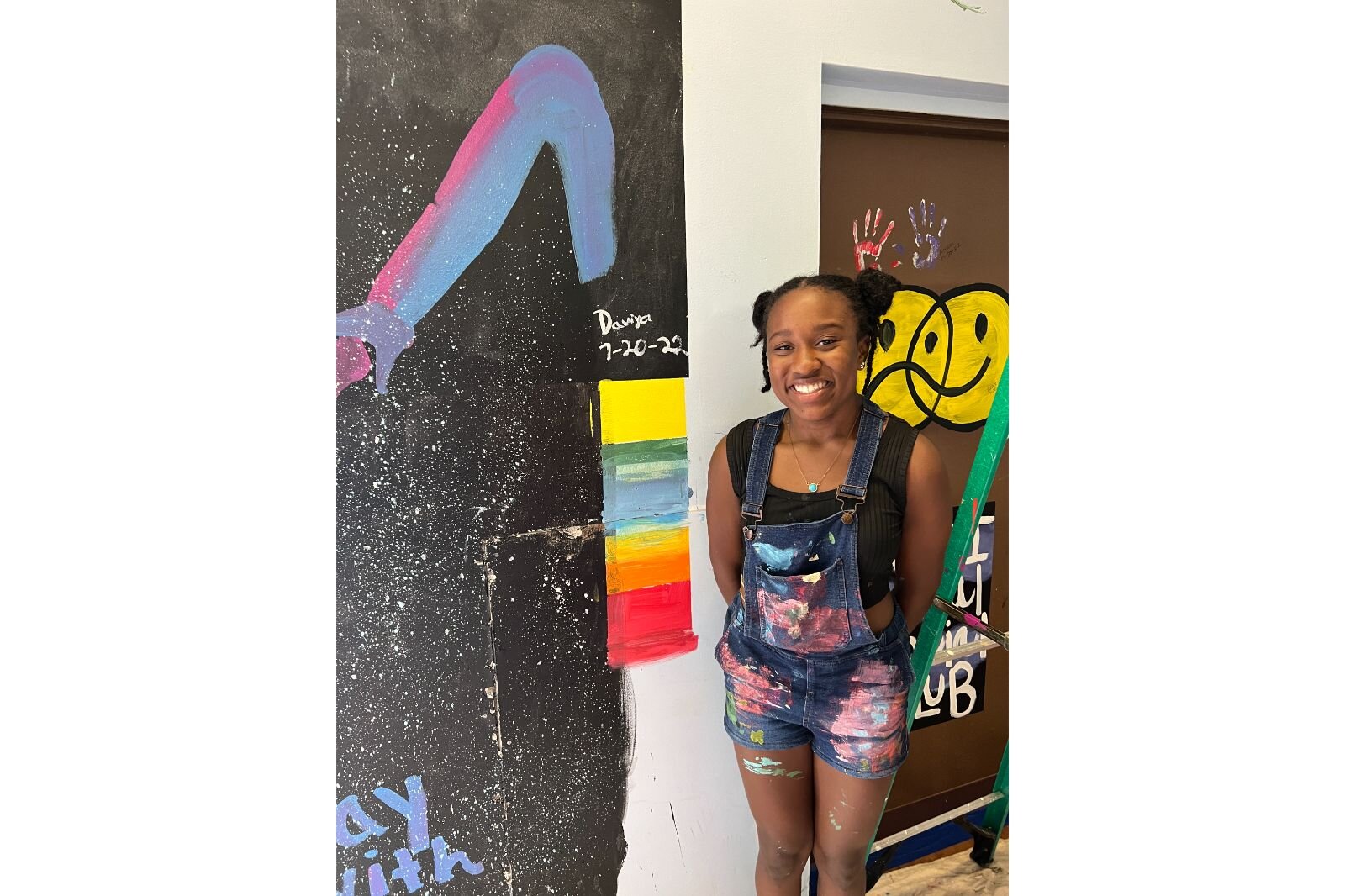 Davia McCoy poses by her mural.