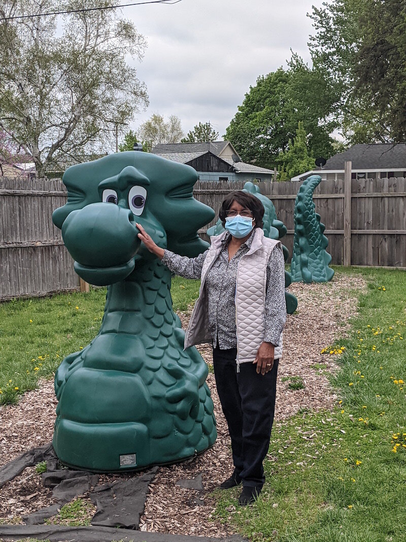 Maude Bristol-Perry, owner of Sugar and Spice Childcare Center, poses with a dragon that is among a wide variety of playground equipment in the backyard of the center.
