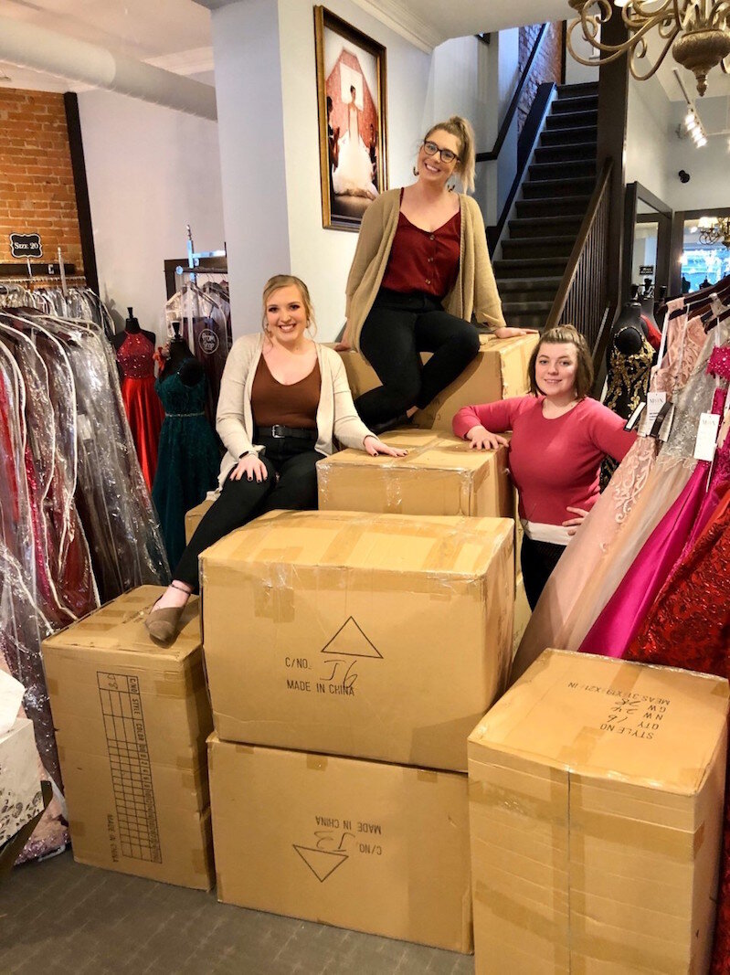Staff members at Memories Bridal & Evening Wear are shown earlier in the season preparing to inbox and display a huge shipment of more than 250 prom dresses. From left, they are: Jodi Isaacson (consultant), Kelsey Klug (store manager) and Mae Bright 
