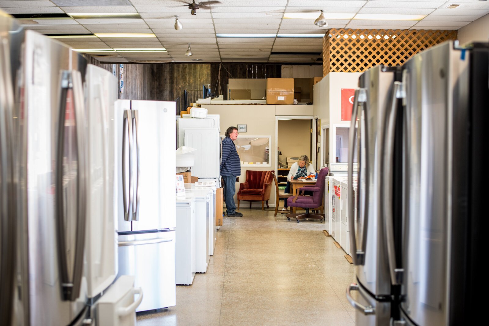 Tom Miyagawa stands inside the family-owned business Monday as his wife, Mary, performs some paperwork. She serves as bookkeeper for the business.