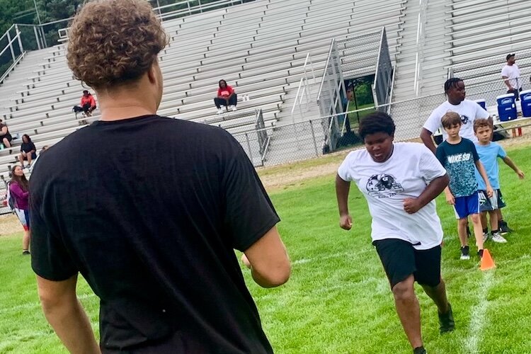 A varsity high school plater helps kids do football drills at the Kalamazoo Youth Football Camp, held Saturday, Aug. 26, 2025 at Mayor’s Riverfront Park.