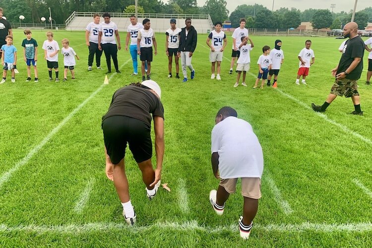 A coach helps a youngster do football drills at the Kalamazoo Youth Football Camp, held Saturday, Aug. 26, 2025 at Mayor’s Riverfront Park.