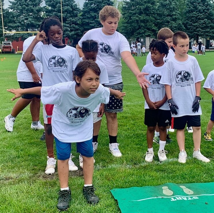 A young football player spreads his arm as he prepares to do a long jump during the Kalamazoo Youth Football Camp, held Saturday, Aug. 26, 2025 at Mayor’s