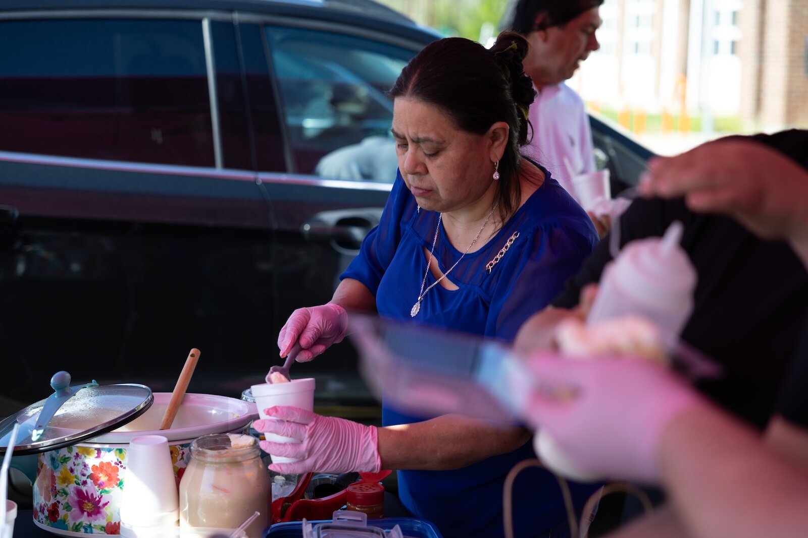 La madre de Esperanza Herrera sirve elote a los clientes en el mercadito.